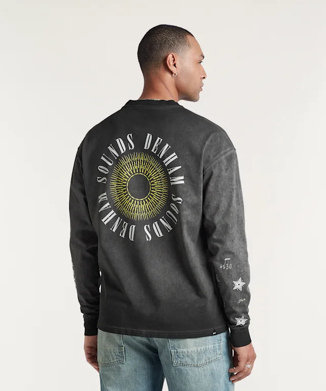 Person wearing a black long-sleeve shirt with a circular design and text on the back, standing against a plain background.