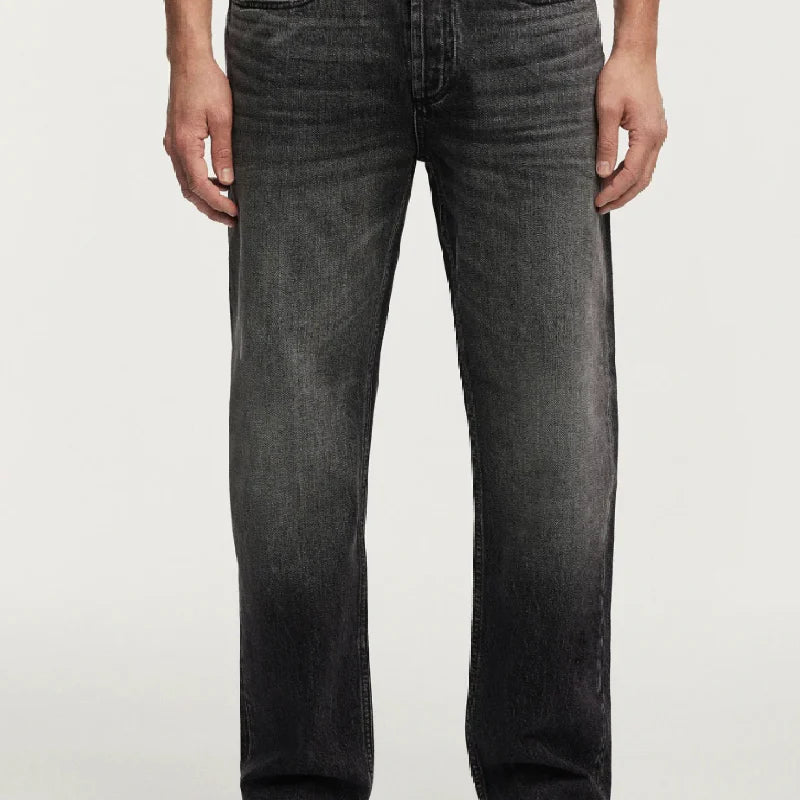 Person wearing black jeans and black shoes on a white background