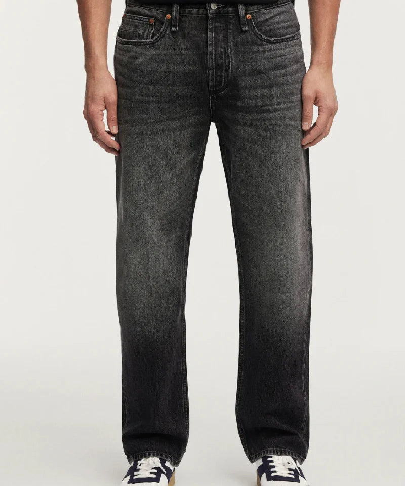 Person wearing black jeans and black shoes on a white background
