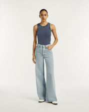 Woman wearing a blue sleeveless top and light blue jeans on a white background