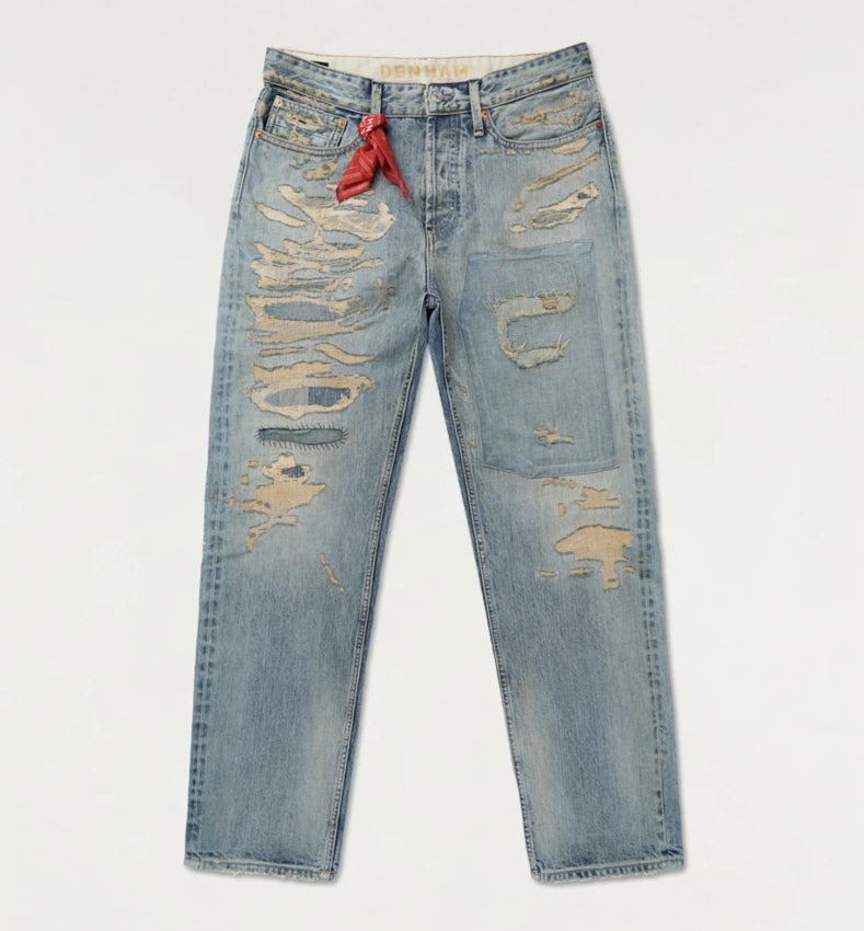 Distressed blue jeans with a red tag on a light gray background